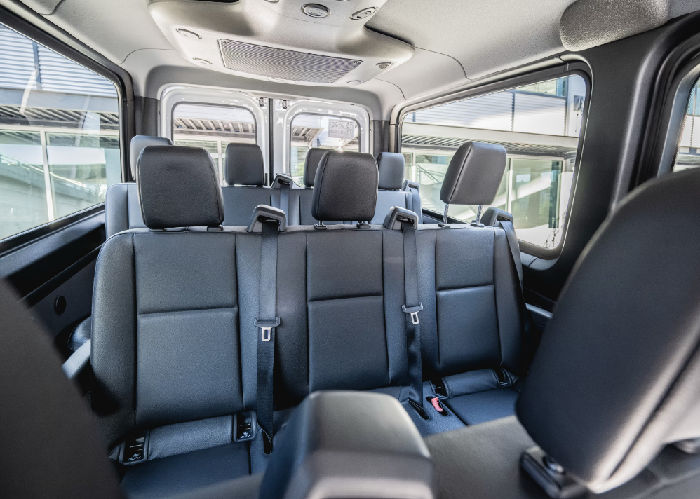 Interior of a Mercedes Sprinter van showing rows of passenger seating and standing headroom